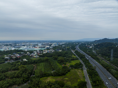 Aerial view of a highway stretching through lush green fields and industrial areas under a cloudy sky in Jiuru Township Pingtung County Taiwan. Aerial view of a highway stretching through lush green fields and industrial areas under a cloudy sky in Jiuru Township Pingtung County Taiwan.
