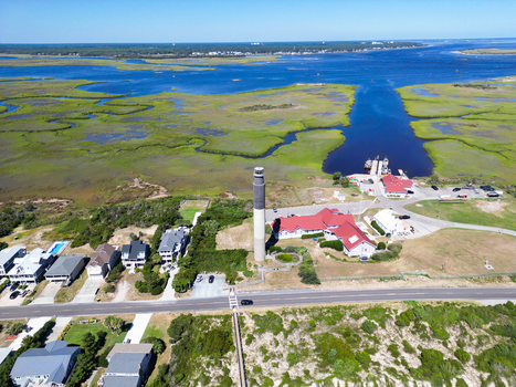 Aerial view of Oak Island Lighthouse surrounded by coastal marshlands and residential buildings in Caswell Beach North Carolina United States.