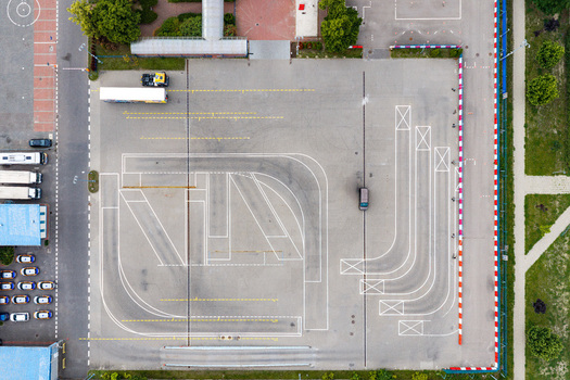 Aerial view of a driving school training course with white painted practice lines and a single car on an asphalt lot in Warsaw Masovian Voivodeship Poland. Aerial view of a driving school training course with white painted practice lines and a single car on an asphalt lot in Warsaw Masovian Voivodeship Poland.