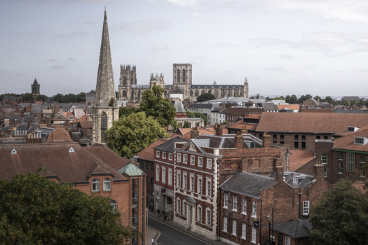 Aerial view of York Minster rising above the historic red brick rooftops and narrow streets of York England United Kingdom.
