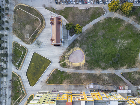 Aerial view of Parku Qendror with its paved pathways green lawns and a small pond surrounded by urban buildings in Fier Fier County Albania.