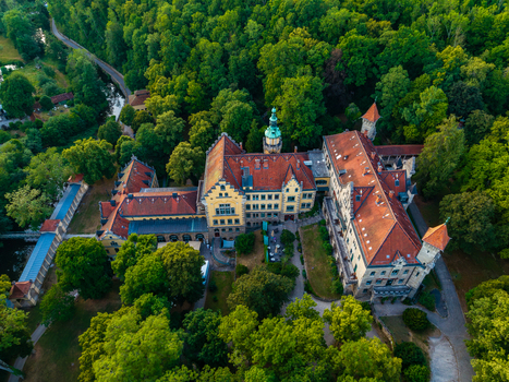 Aerial view of a historic castle complex with red tiled roofs and stone architecture surrounded by lush green forest in Rothenburg ob der Tauber Bavaria Germany. Aerial view of a historic castle complex with red tiled roofs and stone architecture surrounded by lush green forest in Rothenburg ob der Tauber Bavaria Germany.