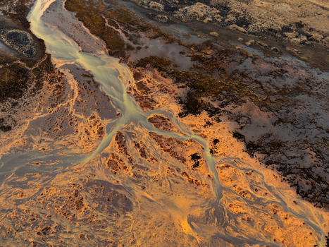 Aerial view of a braided river system flowing through a volcanic landscape with sediment rich water channels illuminated by golden hour light Iceland. Aerial view of a braided river system flowing through a volcanic landscape with sediment rich water channels illuminated by golden hour light Iceland.