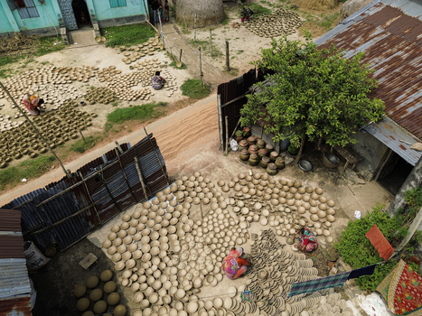 Joypurhat Bangladesh 28 September 2026 Aerial view of artisans arranging clay pots to dry in the sun within a rural village courtyard surrounded by traditional houses and greenery. Joypurhat Bangladesh 28 September 2026 Aerial view of artisans arranging clay pots to dry in the sun within a rural village courtyard surrounded by traditional houses and greenery.