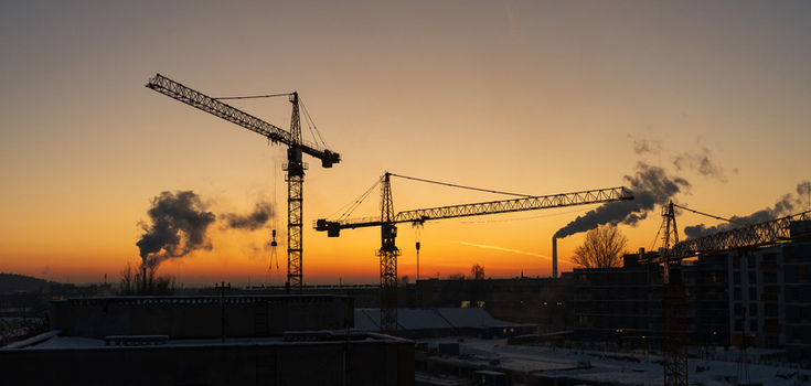View of construction cranes silhouetted against a vibrant sunset sky over industrial buildings in Vilnius Vilnius County Lithuania. View of construction cranes silhouetted against a vibrant sunset sky over industrial buildings in Vilnius Vilnius County Lithuania.