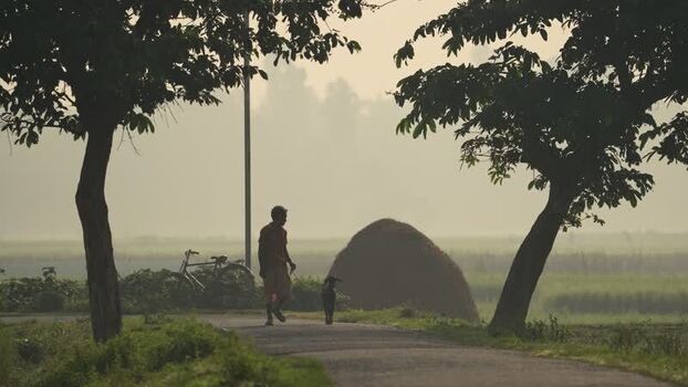 View of a man walking with a goat on a rural road Bangladesh.