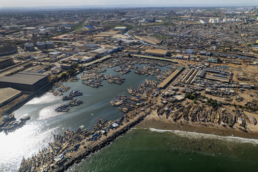 Aerial view of a vibrant port where hundreds of boats gather creating a mosaic of color against the dark water and sandy shore Tema Ghana. Aerial view of a vibrant port where hundreds of boats gather creating a mosaic of color against the dark water and sandy shore Tema Ghana.