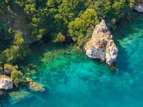 Aerial view of Lake Ohrid with its clear turquoise water rocky shoreline and lush green trees in Ohrid Municipality of Ohrid North Macedonia.