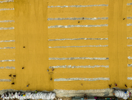 Ashuganj Bangladesh 05 July 2022 Aerial view of workers spreading and drying golden rice grains in long rows on the ground with sacks stacked nearby.
