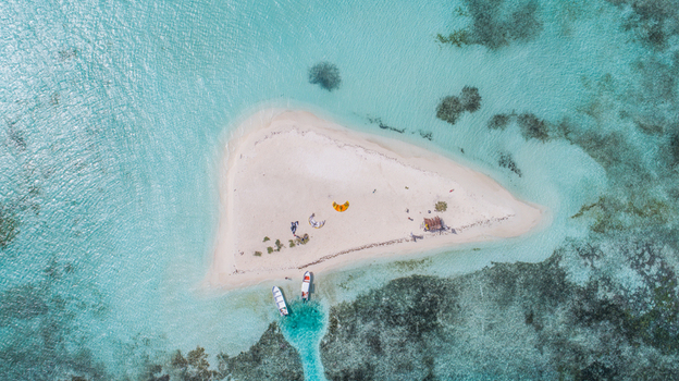 Aerial view of Los Roques archipelago featuring a small sandy cay surrounded by turquoise waters coral reefs and two small boats docked Los Roques Dependencias Federales Venezuela. Aerial view of Los Roques archipelago featuring a small sandy cay surrounded by turquoise waters coral reefs and two small boats docked Los Roques Dependencias Federales Venezuela.
