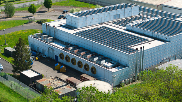 Aerial view of a modern data centre building featuring rooftop solar panels and large industrial cooling fans surrounded by green trees Wellingborough England United Kingdom. Aerial view of a modern data centre building featuring rooftop solar panels and large industrial cooling fans surrounded by green trees Wellingborough England United Kingdom.
