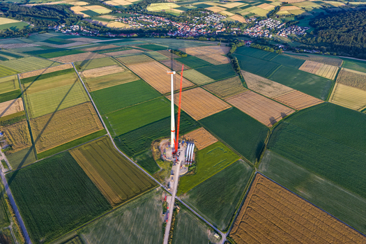Aerial view of a wind turbine under construction in a rural landscape with agricultural fields and a small town in the distance in Hofgeismar Hessen Germany.