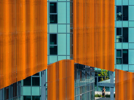 Aerial view of modern building facade with vibrant orange vertical louvers and teal glass panels featuring a person walking on the ground level in Belgrade City of Belgrade Serbia. Aerial view of modern building facade with vibrant orange vertical louvers and teal glass panels featuring a person walking on the ground level in Belgrade City of Belgrade Serbia.