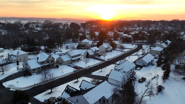 Aerial view of a suburban neighborhood in Warwick Township covered in snow during a golden sunset with light on rooftops and quiet streets Warwick Township Pennsylvania United States.