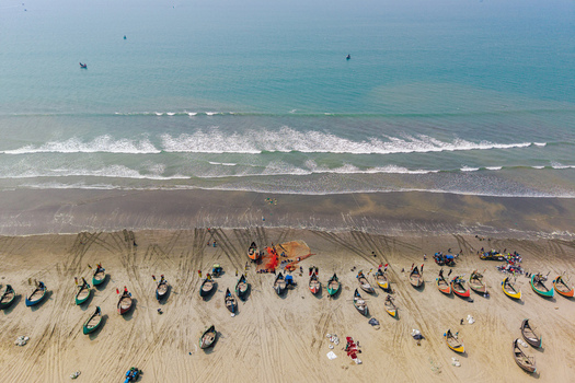 Cox s Bazar Bangladesh 10 March 2026 Aerial view of traditional colorful fishing boats parked on the sandy shore with waves crashing on the beach and people working near the nets. Cox s Bazar Bangladesh 10 March 2026 Aerial view of traditional colorful fishing boats parked on the sandy shore with waves crashing on the beach and people working near the nets.