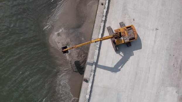Aerial view of yellow excavator on concrete pier Portugal.