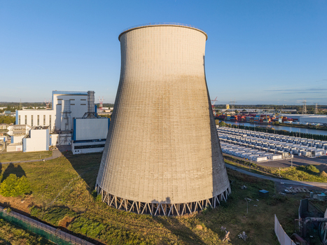 Aerial view of the large concrete cooling tower at the Cargovil industrial site with rows of battery energy storage system containers and infrastructure in Vilvoorde Vlaanderen Belgium. Aerial view of the large concrete cooling tower at the Cargovil industrial site with rows of battery energy storage system containers and infrastructure in Vilvoorde Vlaanderen Belgium.