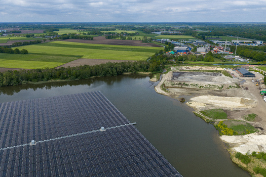Aerial view of floating solar panels on a lake with industrial buildings and green fields under a cloudy sky Beilen Drenthe Netherlands. Aerial view of floating solar panels on a lake with industrial buildings and green fields under a cloudy sky Beilen Drenthe Netherlands.