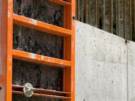 View of orange metal formwork and a textured concrete wall with vertical rebar at a construction site in Sariyer Istanbul Turkey. View of orange metal formwork and a textured concrete wall with vertical rebar at a construction site in Sariyer Istanbul Turkey.