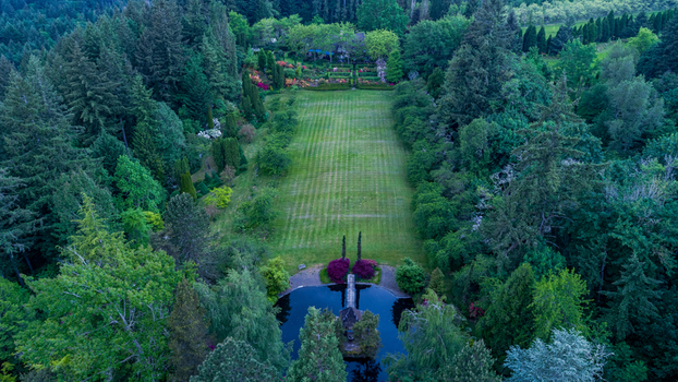 Aerial view of a manicured green lawn surrounded by dense evergreen forests and a small pond near Northwest Skyline Boulevard Portland Oregon United States. Aerial view of a manicured green lawn surrounded by dense evergreen forests and a small pond near Northwest Skyline Boulevard Portland Oregon United States.
