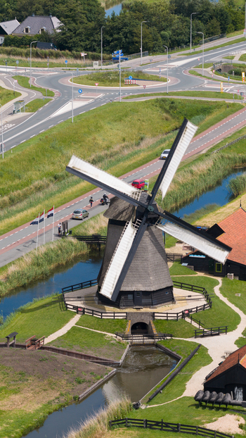 Aerial view of De Museummolen a historic windmill surrounded by a canal green fields and a nearby road in Schermerhorn Noord Holland Netherlands. Aerial view of De Museummolen a historic windmill surrounded by a canal green fields and a nearby road in Schermerhorn Noord Holland Netherlands.