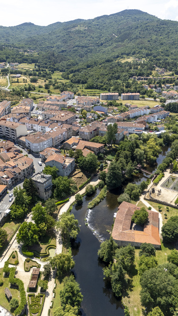 Aerial view of the historic town of Allariz featuring stone buildings a winding river and lush parks surrounded by hills Allariz Province of Ourense Spain. Aerial view of the historic town of Allariz featuring stone buildings a winding river and lush parks surrounded by hills Allariz Province of Ourense Spain.