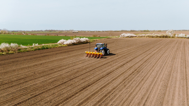 Aerial view of a vibrant blue tractor cutting through the rich brown earth preparing the fields for planting Sremska Mitrovica Vojvodina Serbia. Aerial view of a vibrant blue tractor cutting through the rich brown earth preparing the fields for planting Sremska Mitrovica Vojvodina Serbia.