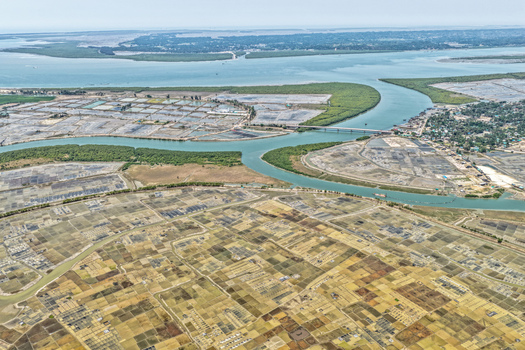 Aerial view of a river snaking through a landscape mosaic of salt pans and aquaculture farms under a vast sky Cox s Bazar Chittagong Division Bangladesh. Aerial view of a river snaking through a landscape mosaic of salt pans and aquaculture farms under a vast sky Cox s Bazar Chittagong Division Bangladesh.