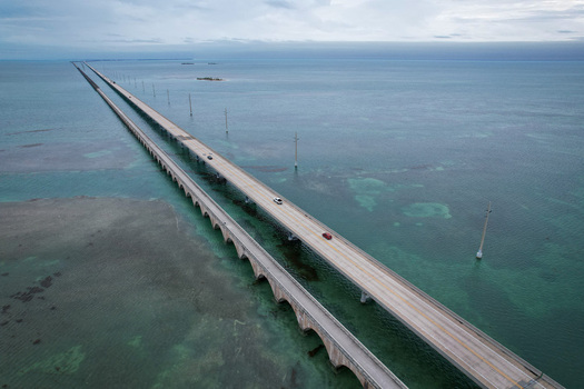 Aerial view of The Overseas Highway stretching across turquoise waters with cars driving and the old bridge alongside in Key Largo Florida United States. Aerial view of The Overseas Highway stretching across turquoise waters with cars driving and the old bridge alongside in Key Largo Florida United States.