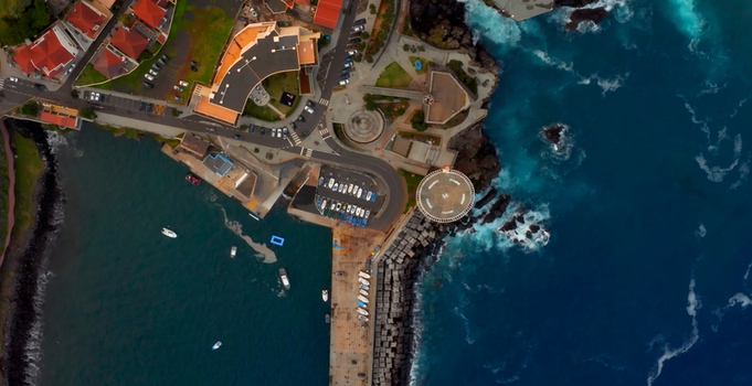Aerial view of the coastal town of Porto Moniz featuring its natural volcanic pools a small harbor with moored boats and surrounding buildings along the rugged Atlantic coastline in Porto Moniz Madeira Portugal. Aerial view of the coastal town of Porto Moniz featuring its natural volcanic pools a small harbor with moored boats and surrounding buildings along the rugged Atlantic coastline in Porto Moniz Madeira Portugal.
