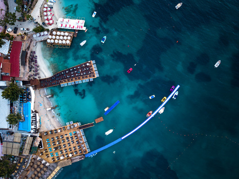 Aerial view of turquoise waters and wooden piers with sunbeds along the white sandy coastline of Ksamil Vlore County Albania. Aerial view of turquoise waters and wooden piers with sunbeds along the white sandy coastline of Ksamil Vlore County Albania.