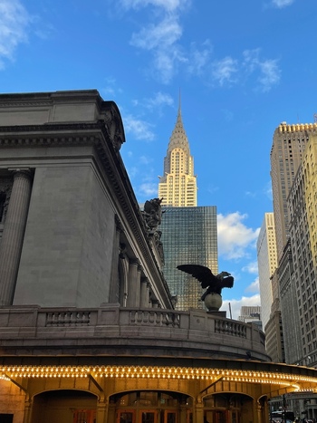 View of the historic Grand Central Terminal facade featuring an eagle statue and illuminated marquee with the Chrysler Building in the background New York New York United States. View of the historic Grand Central Terminal facade featuring an eagle statue and illuminated marquee with the Chrysler Building in the background New York New York United States.