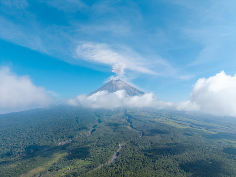 Aerial view of Mount Semeru with volcanic smoke rising from the peak surrounded by lush green forests and clouds in Pronojiwo East Java Indonesia. Aerial view of Mount Semeru with volcanic smoke rising from the peak surrounded by lush green forests and clouds in Pronojiwo East Java Indonesia.