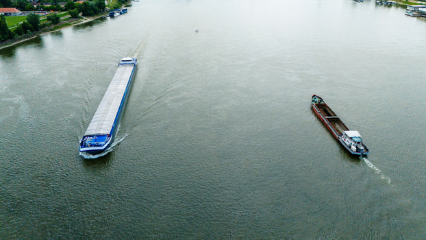 Aerial view of two cargo barges navigating the calm waters of a wide river with green banks in Novi Sad Vojvodina Serbia. Aerial view of two cargo barges navigating the calm waters of a wide river with green banks in Novi Sad Vojvodina Serbia.