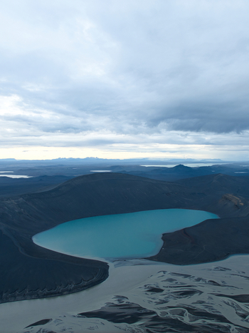 Aerial view of Skyggnisvatn crater lake with its turquoise water surrounded by dark volcanic slopes and a braided river in Hella Rangarthing ytra Iceland. Aerial view of Skyggnisvatn crater lake with its turquoise water surrounded by dark volcanic slopes and a braided river in Hella Rangarthing ytra Iceland.