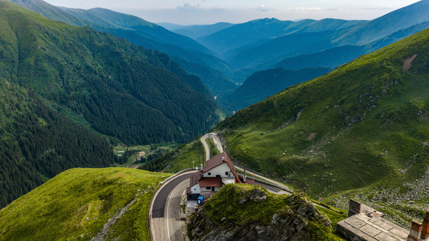 Aerial view of Transfagarasan mountain road winding through the Carpathian Mountains with a lodge perched on the ridge in Curtea de Arges Judetul Arges Romania.