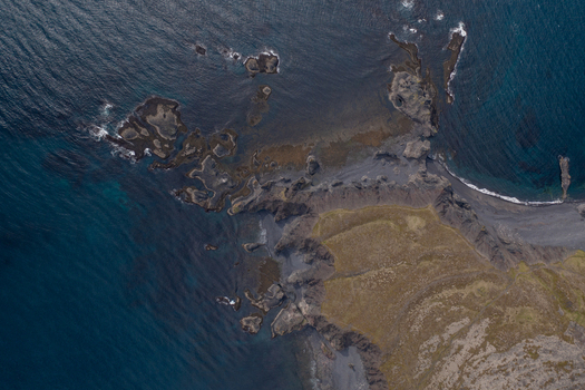 Aerial view of Djupalonssandur featuring dark volcanic sand beaches rugged rock formations and deep blue ocean waters in Iceland. Aerial view of Djupalonssandur featuring dark volcanic sand beaches rugged rock formations and deep blue ocean waters in Iceland.