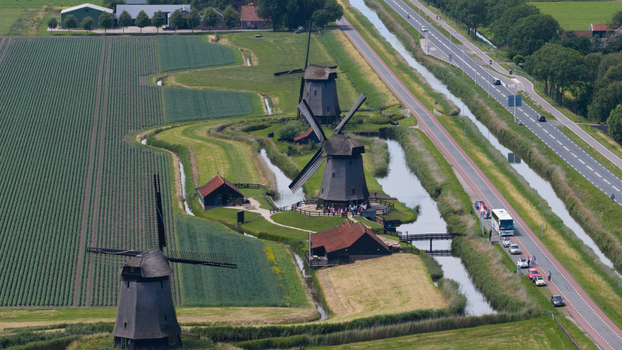 Aerial view of the historic windmills in Schermerhorn surrounded by green fields canals and a nearby road in Schermerhorn North Holland Netherlands. Aerial view of the historic windmills in Schermerhorn surrounded by green fields canals and a nearby road in Schermerhorn North Holland Netherlands.