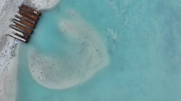 Aerial view of industrial pipes on a sandy beach in Gulhi Maldives.