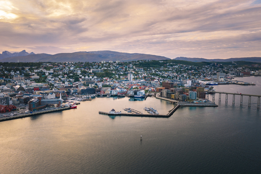 Aerial view of the city of Tromso featuring the harbor modern buildings and the bridge under a soft late summer sky in Tromso Troms Norway. Aerial view of the city of Tromso featuring the harbor modern buildings and the bridge under a soft late summer sky in Tromso Troms Norway.