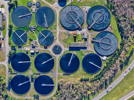 Aerial view of circular water treatment tanks reflecting the sky contrasted by the surrounding verdant landscape Sausheim Grand Est France.