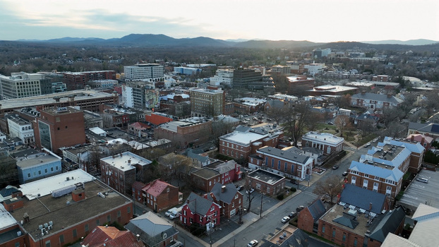 Aerial view of Charlottesville at sunset featuring historic brick buildings urban streets and distant mountains under a soft evening sky in Charlottesville Virginia United States. Aerial view of Charlottesville at sunset featuring historic brick buildings urban streets and distant mountains under a soft evening sky in Charlottesville Virginia United States.