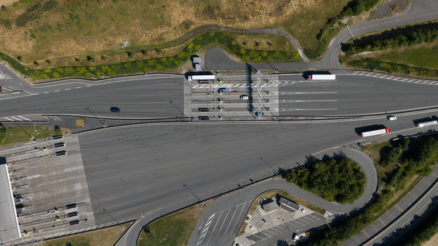 Aerial view of Gare de Peage de Dury toll station with vehicles passing through lanes surrounded by green fields and asphalt roads in Saleux Hauts de France France.