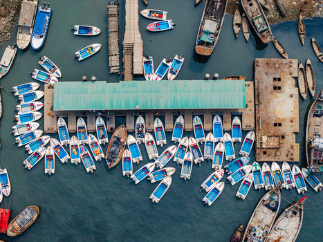 Moheskhali Upazila Bangladesh 11 March 2026 Aerial view of numerous small motorboats and wooden vessels docked at a jetty with a green roof and people on the pier. Moheskhali Upazila Bangladesh 11 March 2026 Aerial view of numerous small motorboats and wooden vessels docked at a jetty with a green roof and people on the pier.