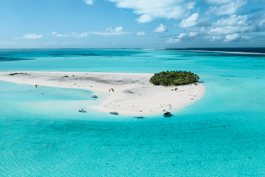 Aerial view of Aitutaki island with white sand beaches turquoise lagoon waters palm trees and small boats anchored nearby under a bright blue sky Cook Islands. Aerial view of Aitutaki island with white sand beaches turquoise lagoon waters palm trees and small boats anchored nearby under a bright blue sky Cook Islands.