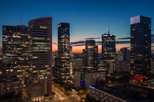 Warszawa Poland 10 September 2026 Aerial view of Q22 and the surrounding modern skyscrapers in the city skyline at dusk with glowing office lights and a vibrant sunset sky.