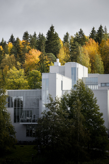 View of a modern building with white facade and large glass windows nestled among vibrant autumn trees in the forest in Jyvaskyla Central Finland Finland.