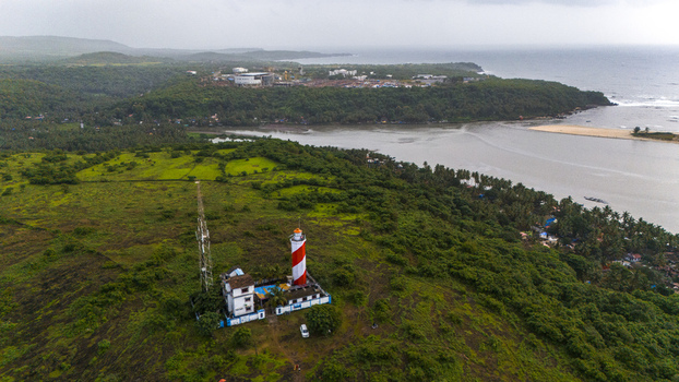 Aerial view of Betul Lighthouse with its red and white striped tower on lush green hills overlooking the river estuary and Arabian Sea in Kital Goa India.