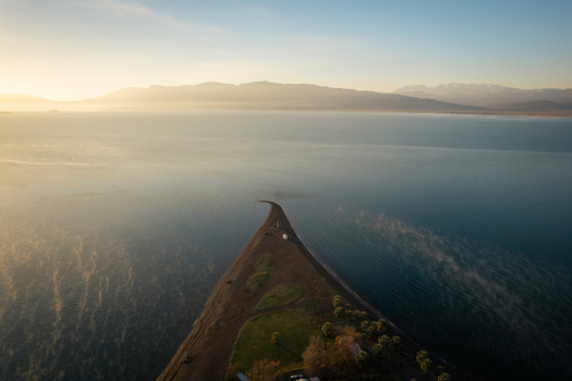 Aerial view of the triangular spit of land in Itea extending into the calm sea during golden hour with mountains in the background Itea Greece.