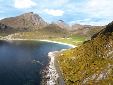 Aerial view of Vik Strand beach with turquoise water a winding coastal road and rugged mountains under a blue sky in Leknes Nordland Norway. Aerial view of Vik Strand beach with turquoise water a winding coastal road and rugged mountains under a blue sky in Leknes Nordland Norway.